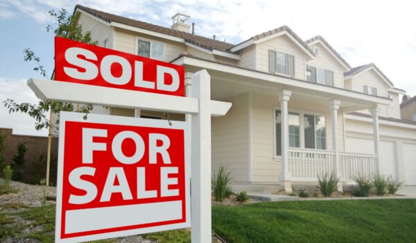 A For Sale Sign With A Sold Sign On It Infront of A House In California