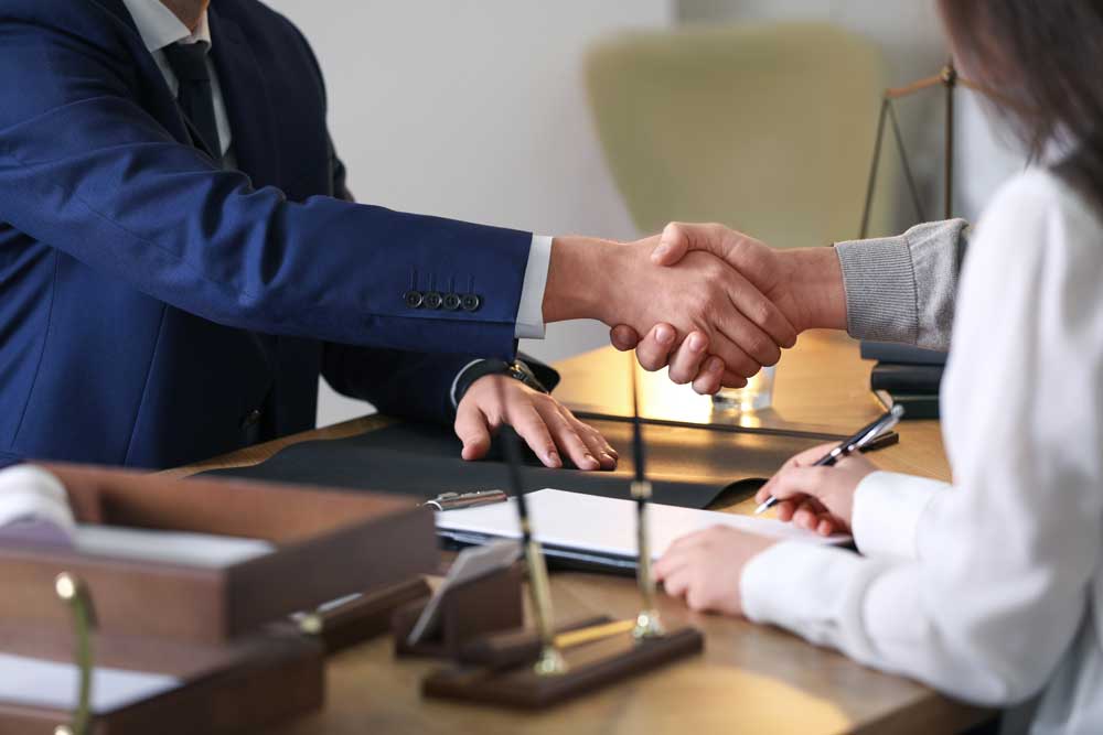 A real estate attorney and a client shake hands