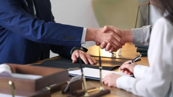 An attorney shakes hands with a client during an estate planning meeting
