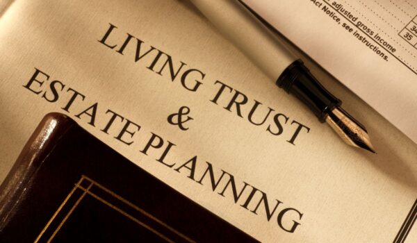 Image of a document and a pen, tucked inside a folder, saying living will and estate planning